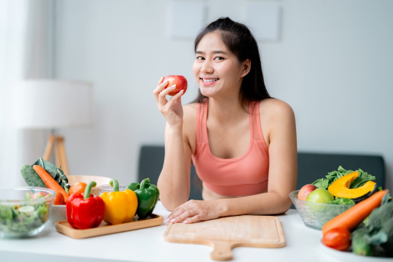 happy young woman eating an apple promoting healthy eating habits for a wellness lifestyle